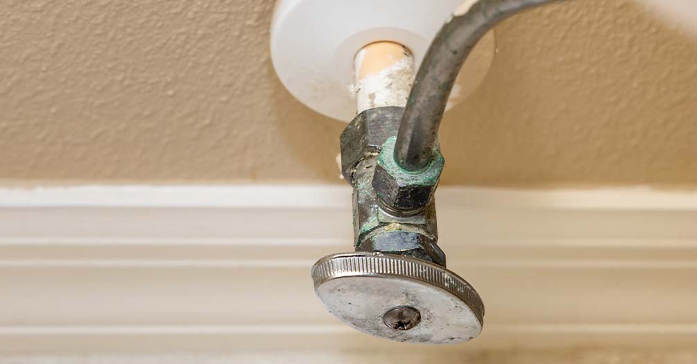 Shut-off valve with green, chalky corrosion forming around the fitting